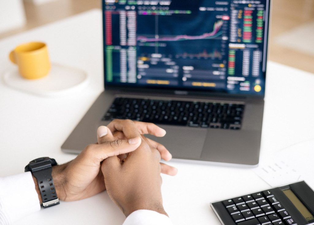 man sitting next to laptop using nadex platform